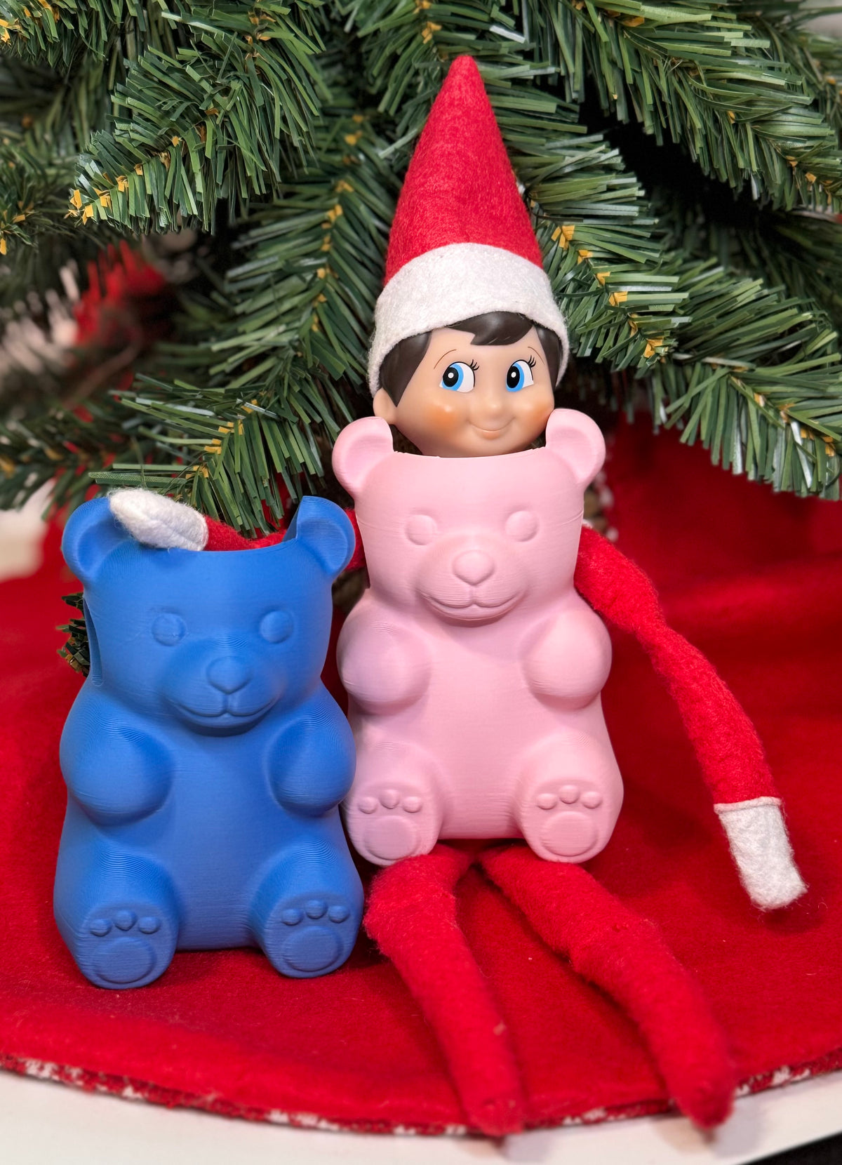 Pink and blue 3D printed gummy bear elf costumes under a Christmas tree
