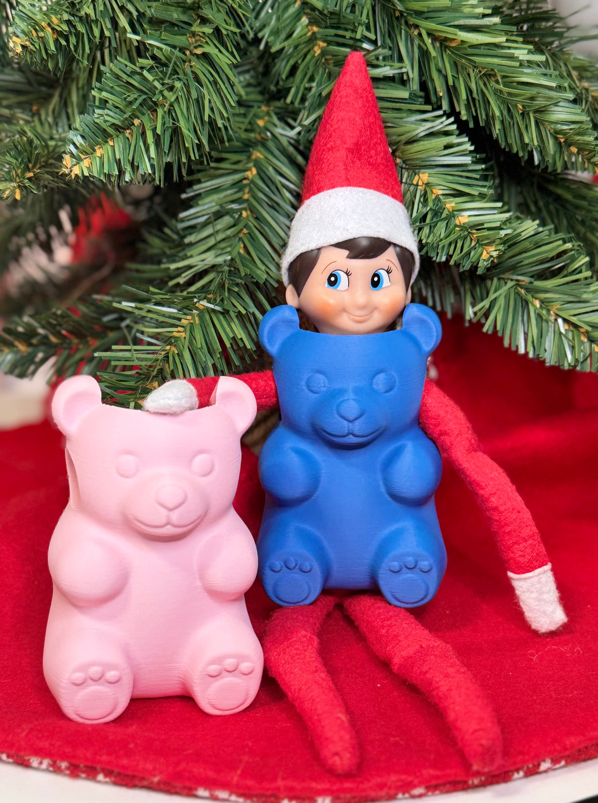 Pink and blue 3D printed gummy bear elf costumes under a Christmas tree